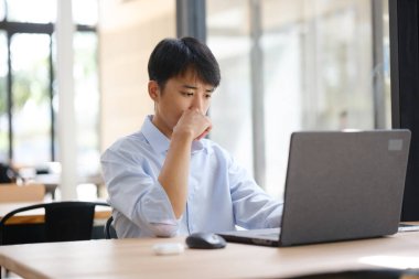 Odaklanmış bir iş danışmanı dizüstü bilgisayar üzerinde çalışıyor, mali verileri ve yatırım raporlarını analiz ediyor. Yoğunlaştırılmış ifadesi stratejik planlama, muhasebe veya piyasa araştırması öneriyor..