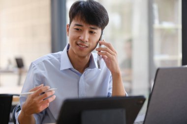 Akıllı telefon ve tabletle birden fazla iş yapan bir işletme danışmanı, mali stratejiler, yatırım planlaması veya uzaktan çalışırken iş danışmanlığı hakkında bir tartışmaya girişir..