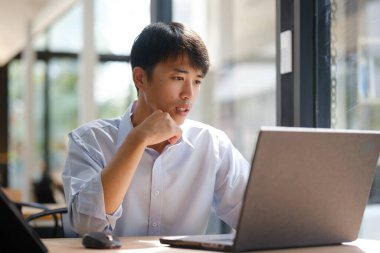 Dizüstü bilgisayarda çalışan bir iş adamı, finansal analiz, yatırım planlaması ya da iş danışmanlığı yapıyor. Çevrimiçi iş, muhasebe veya strateji geliştirme için teknoloji kullanılıyor.