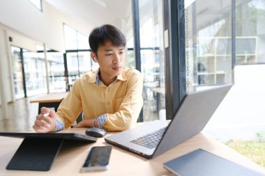 Sınavlara hazırlanmak için çevrimiçi öğrenim gören, notlar alan ve çalışma materyallerini kitaplarla ve dijital cihazlarla inceleyen bir öğrenci.