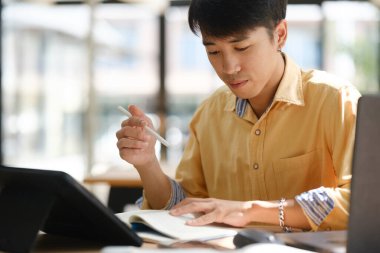 Bir üniversite öğrencisi sınavlara hazırlanmak için ders kitabı okumaya odaklandı. Önemli akademik materyalleri öğrenmekle ve incelemekle meşgul..