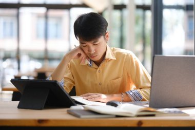 Bir üniversite öğrencisi notları gözden geçirmeye ve yaklaşan sınav için çalışmaya derinden odaklanmıştı. Anlama ve tutmayı geliştirmek için anahtar bilgileri organize ediyor..