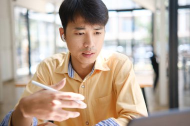 Sınavlara hazırlanmak için çevrimiçi öğrenim gören, notlar alan ve çalışma materyallerini kitaplarla ve dijital cihazlarla inceleyen bir öğrenci.