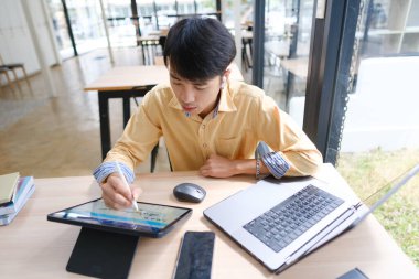 Sınavlara hazırlanmak için çevrimiçi öğrenim gören, notlar alan ve çalışma materyallerini kitaplarla ve dijital cihazlarla inceleyen bir öğrenci.