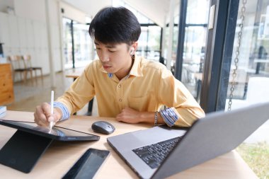 Sınavlara hazırlanmak için çevrimiçi öğrenim gören, notlar alan ve çalışma materyallerini kitaplarla ve dijital cihazlarla inceleyen bir öğrenci.