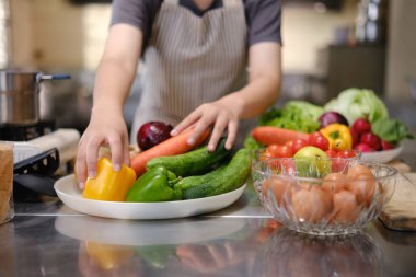 Aşçılık öğrencisi profesyonel bir eğitim mutfağında pratik ve öğrenme için hazırlanmış taze malzemelerle elleriyle yemek pişirmeye hazır bekliyor..