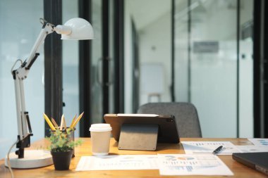 Finansal tablolar, tablet ve kahve ile birlikte temiz ve modern bir ofis masası, iş analizi için hazır..