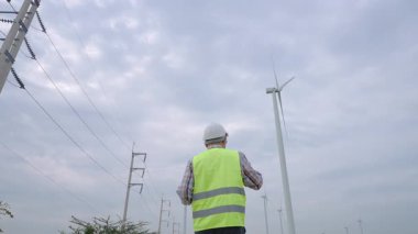 Rüzgar türbini alanından geçen mühendis yenilenebilir enerji altyapısını inceliyor. Yüksek kalite 4k görüntü