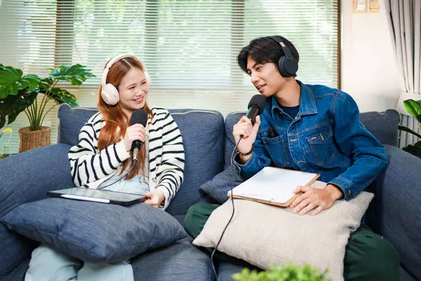 Genç adam ve kadın evlerinde kulaklık ve mikrofonla podcast yaparken masada ses mikseriyle oturuyorlar..