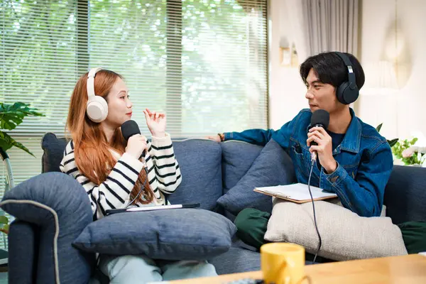 Genç adam ve kadın evlerinde kulaklık ve mikrofonla podcast yaparken masada ses mikseriyle oturuyorlar..
