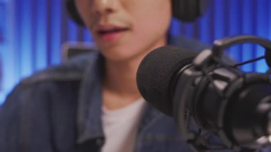 Bir podcast veya canlı yayın kaydı sırasında içerik yaratıcısı tarafından kullanılan profesyonel mikrofonun makro görüntüsü