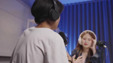 Bir erkek podcast konuğu, podcast kaydı sırasında düşüncelerini paylaşıyor. Sunucu arka planda dikkatlice dinliyor..