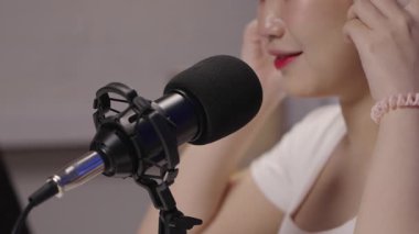 Canlı yayın sırasında profesyonel bir mikrofona konuşan bir podcast sunucusunun kapatılması, ses netliği ve modern içerik oluşturulmasının vurgulanması.