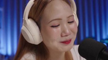 Mikrofonla konuşan ve stüdyoda podcast yapan neşeli Asyalı genç kadın radyo sunucusunu ya da podcaster flamasını kapatın.
