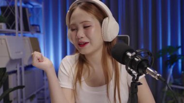 Modern bir kapalı mekan ortamında canlı yayın sırasında yorumları yanıtlayarak, podcast sunucusunu izleyicilerle etkileşime sokarak ortamı kapat.