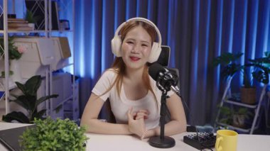 Bir podcast sunucusunun samimi ve kendinden emin konuşması, dinleyicileri sıcak ve modern bir stüdyo ortamında kendine çeken orta ölçekli bir çekimi..