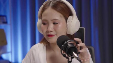 Bir podcast sunucusu, canlı yayın sırasında seyirciye samimi bir gülümsemeyle sesleniyor..