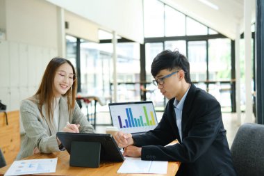 İki profesyonel mali tabloları gözden geçirir ve takım toplantısında yatırım stratejisini tartışır.