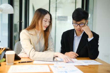 İki profesyonel mali tabloları gözden geçirir ve takım toplantısında yatırım stratejisini tartışır.