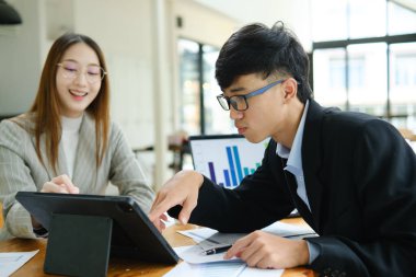 İki profesyonel mali tabloları gözden geçirir ve takım toplantısında yatırım stratejisini tartışır.
