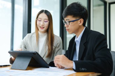 İki profesyonel mali tabloları gözden geçirir ve takım toplantısında yatırım stratejisini tartışır.