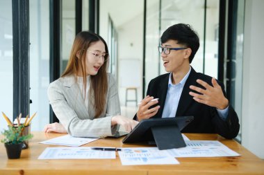 İki profesyonel mali tabloları gözden geçirir ve takım toplantısında yatırım stratejisini tartışır.