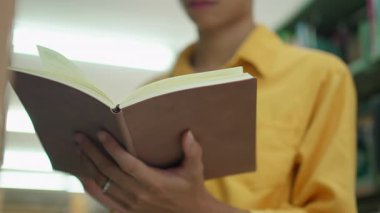 Sayfa kitabını çeviren erkek ellerinin yakın çekimi. Kitap okuyan kadın..