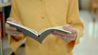 Sayfa kitabını çeviren erkek ellerinin yakın çekimi. Kitap okuyan kadın..