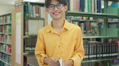 Bir proje için araştırma yapan ya da üniversite kütüphanesinde sınava hazırlanan genç bir erkek öğrenci. Kütüphanede kitap okuyan kendinden emin üniversite öğrencisi.