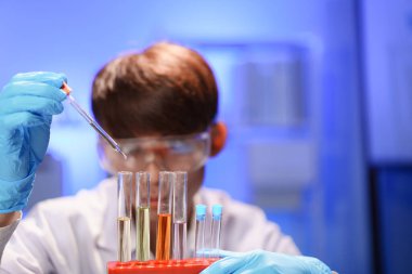 Steril bir laboratuvarda çalışan bilim adamı dikkatlice test tüpüne ölçülmüş bir sıvı ekler. Bu da kimyasal reaksiyonun her damlasının incelenmesini sağlar..