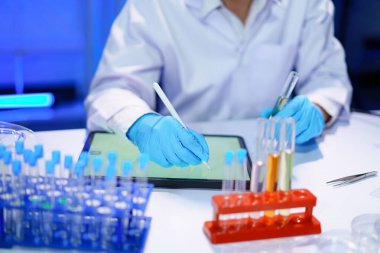 Bilim adamları test sonuçları ve tüp sıvısı reaktörü yazıyorlar. Kimya laboratuvarında laboratuvar bilimcisi.