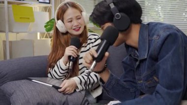 Neşeli radyo sunucusu, iş arkadaşıyla birlikte podcast 'i gösteriyor. Evdeki podcast stüdyosunda eğleniyor, konuşuyor ve kayıt yapıyor..