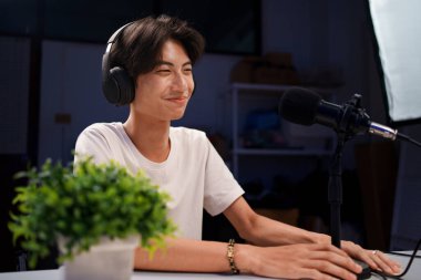 Gülümseyen Asyalı genç radyo sunucuları kulaklıklarla, mikrofonla konuşurken, sohbet ederken, stüdyoda podcast yaparken..