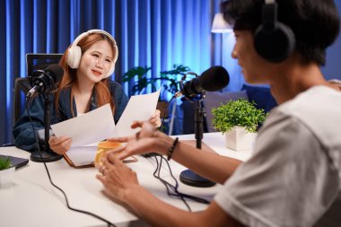 Genç adam ve kadın küçük yayın stüdyosunda mikrofon ve dizüstü bilgisayar kullanarak canlı yayın yapan radyo yayını için röportaj yapacaklar.,