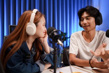 Genç adam ve kadın küçük yayın stüdyosunda mikrofon ve dizüstü bilgisayar kullanarak canlı yayın yapan radyo yayını için röportaj yapacaklar.,