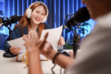 Genç adam ve kadın küçük yayın stüdyosunda mikrofon ve dizüstü bilgisayar kullanarak canlı yayın yapan radyo yayını için röportaj yapacaklar.,