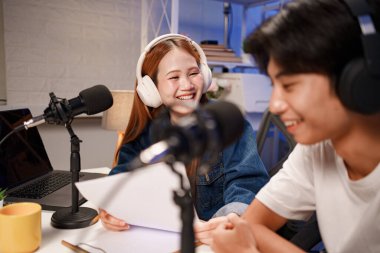 Genç adam ve kadın küçük yayın stüdyosunda mikrofon ve dizüstü bilgisayar kullanarak canlı yayın yapan radyo yayını için röportaj yapacaklar.,