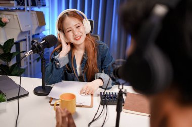 Genç adam ve kadın küçük yayın stüdyosunda mikrofon ve dizüstü bilgisayar kullanarak canlı yayın yapan radyo yayını için röportaj yapacaklar.,