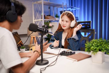 Genç adam ve kadın küçük yayın stüdyosunda mikrofon ve dizüstü bilgisayar kullanarak canlı yayın yapan radyo yayını için röportaj yapacaklar.,