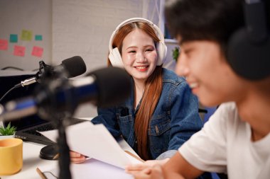 Genç adam ve kadın küçük yayın stüdyosunda mikrofon ve dizüstü bilgisayar kullanarak canlı yayın yapan radyo yayını için röportaj yapacaklar.,