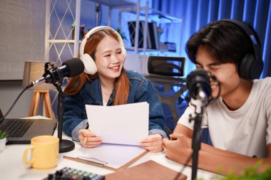 Genç adam ve kadın küçük yayın stüdyosunda mikrofon ve dizüstü bilgisayar kullanarak canlı yayın yapan radyo yayını için röportaj yapacaklar.,