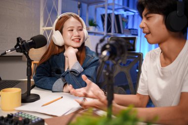 Genç adam ve kadın küçük yayın stüdyosunda mikrofon ve dizüstü bilgisayar kullanarak canlı yayın yapan radyo yayını için röportaj yapacaklar.,