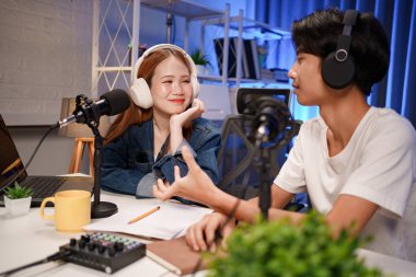 Genç adam ve kadın küçük yayın stüdyosunda mikrofon ve dizüstü bilgisayar kullanarak canlı yayın yapan radyo yayını için röportaj yapacaklar.,