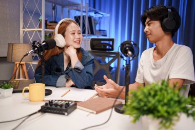 Genç adam ve kadın küçük yayın stüdyosunda mikrofon ve dizüstü bilgisayar kullanarak canlı yayın yapan radyo yayını için röportaj yapacaklar.,