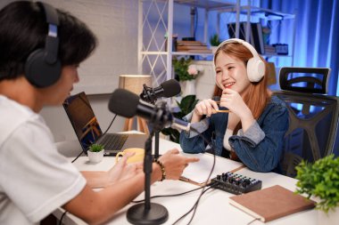 Genç adam ve kadın küçük yayın stüdyosunda mikrofon ve dizüstü bilgisayar kullanarak canlı yayın yapan radyo yayını için röportaj yapacaklar.,