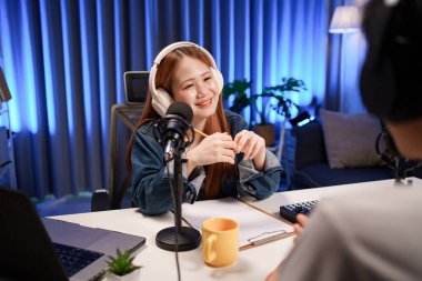 Genç adam ve kadın küçük yayın stüdyosunda mikrofon ve dizüstü bilgisayar kullanarak canlı yayın yapan radyo yayını için röportaj yapacaklar.,