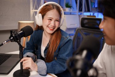 Genç adam ve kadın küçük yayın stüdyosunda mikrofon ve dizüstü bilgisayar kullanarak canlı yayın yapan radyo yayını için röportaj yapacaklar.,