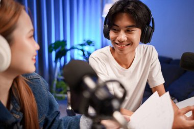 Genç adam ve kadın küçük yayın stüdyosunda mikrofon ve dizüstü bilgisayar kullanarak canlı yayın yapan radyo yayını için röportaj yapacaklar.,
