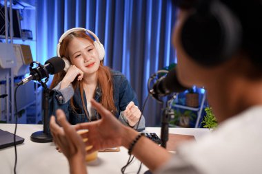 Genç adam ve kadın küçük yayın stüdyosunda mikrofon ve dizüstü bilgisayar kullanarak canlı yayın yapan radyo yayını için röportaj yapacaklar.,