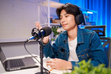 Genç adam gece podcast kaydı sırasında fikirleri anlamlı el hareketleriyle açıklıyor..